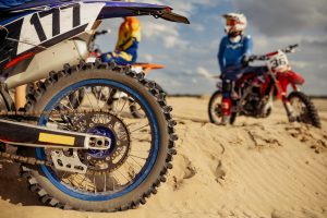 Professional motocross driver on extreme desert terrain track. Focus on rear motorcycle wheel