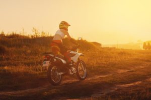 Woman biker rides in fields. Sporty woman biker at motobike. Countryside, country road. sunset, female motorcycle rider, motorbike rider travel the world, girl resting, freedom lifestyle, back view