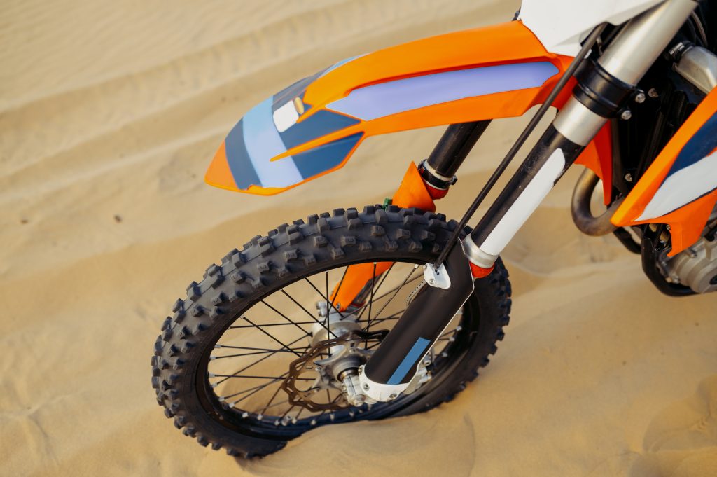 Closeup tire of sport motorcycle with soft-focus. Motocross bike wheel over sand top view