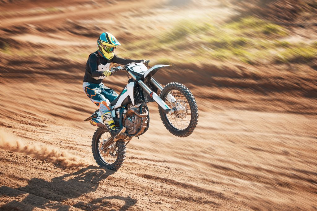 Motorcycle, dirt track stunt and air jump in desert, sand trail and freedom. Driver, cycling and of.